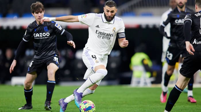 Real Madrid striker Karim Benzema dribbles around Real Sociedad defenders.